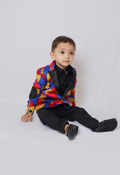 a little boy sitting on the ground wearing a colorful suit